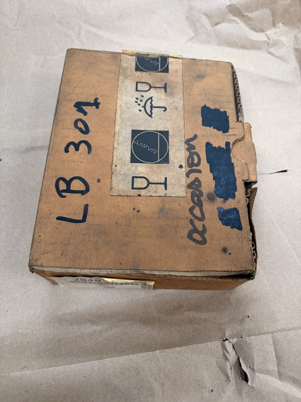 Cardboard box with shipping labels and markings on a white surface