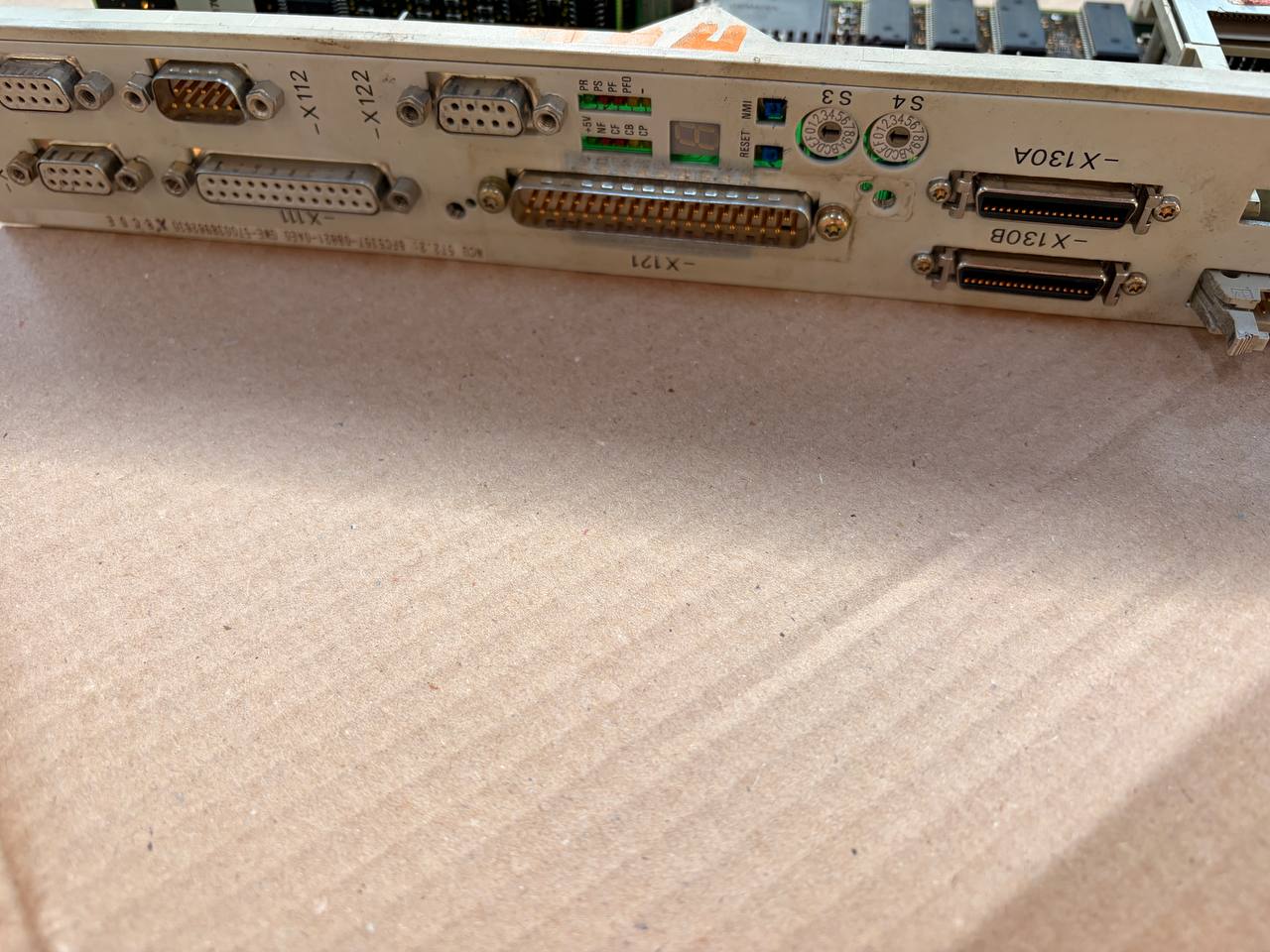 Close-up of a computer motherboard with various ports on a beige surface