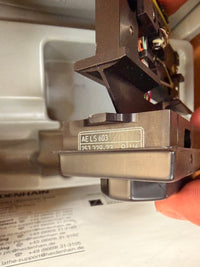 Close-up of a mechanical component with a label, likely from a machine or appliance.