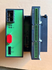 Heidenhain electronic modules, one green with a red button and the other black with green connectors, on a beige surface.