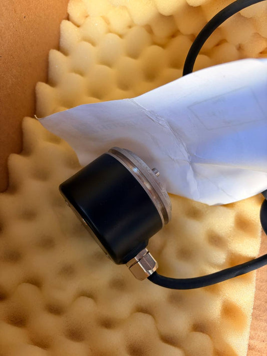 Heidenhain encoder - Black and white handheld device on a textured yellow surface