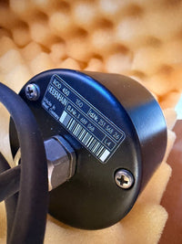 Heidenhain ROD Encoder Close-up of a black cylindrical device with text and a barcode on a blurred background