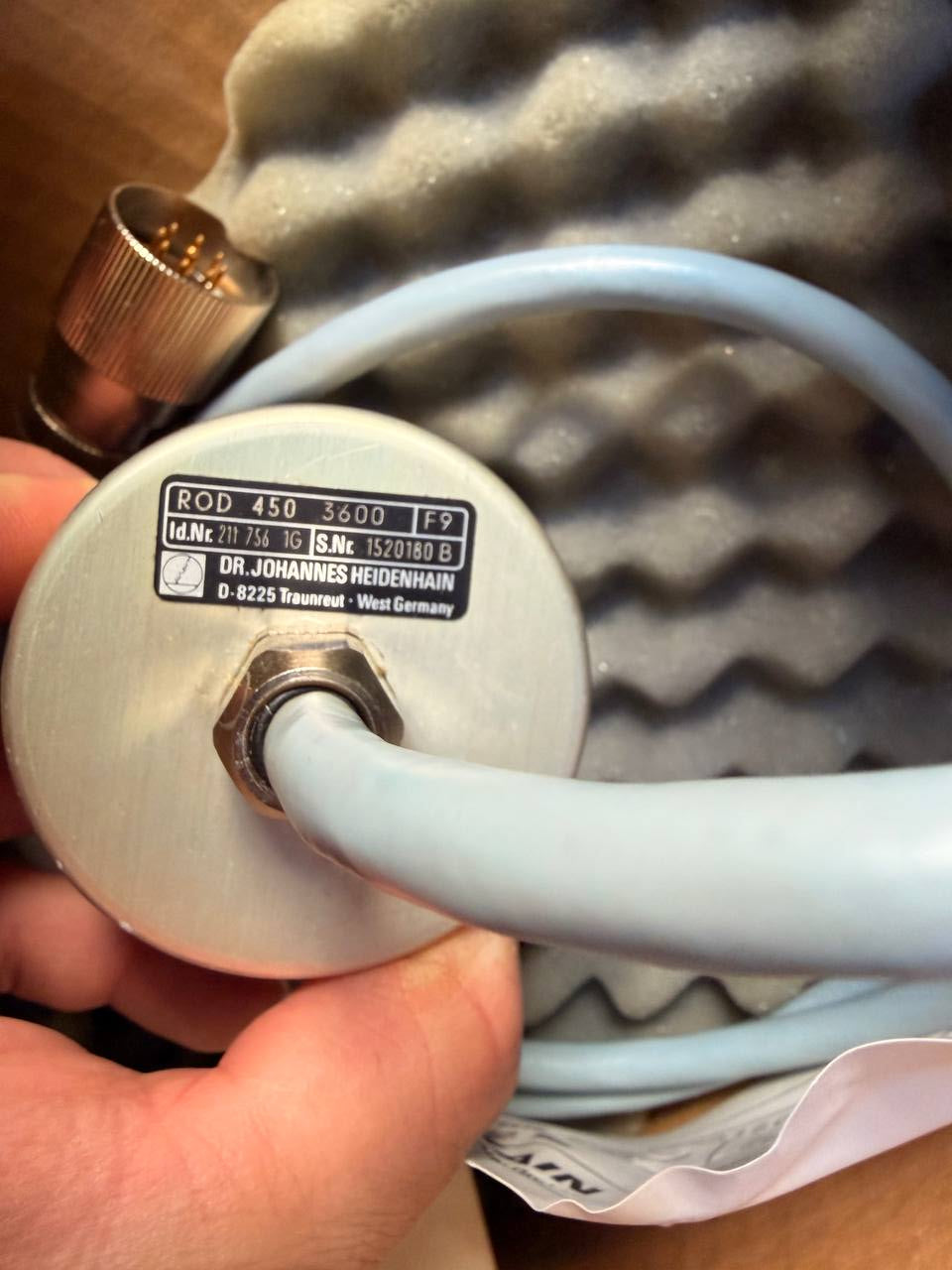Close-up of a hand holding a white hose connected to a device with visible branding.