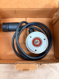Mechanical component with black cable inside a cardboard box