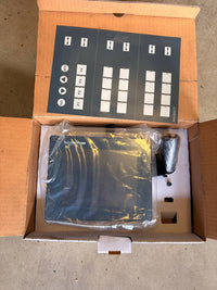 Open cardboard box containing electronic components with labels on a concrete floor.