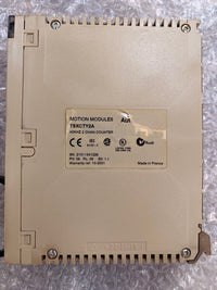 A beige industrial motion control module labeled TSXOTY2A, photographed from above on a crinkled bubble wrap surface. The back shows screw terminals, ribbed edges, and a central specification sticker.