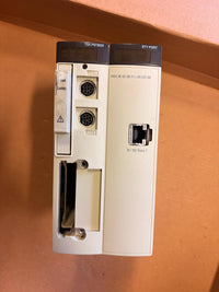 A Siemens industrial automation module, specifically a TSX P07083 and ETY PORT 1 pair, in a beige plastic housing with dark gray top panels, photographed on a brown cardboard surface.
