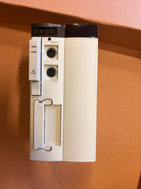 A TSX P57303A industrial card reader module with a white plastic body, black top panel, and card slot, photographed on a brown cardboard surface.
