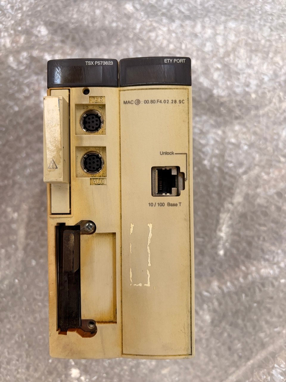 A vintage beige industrial electronic module with black connectors and labels, photographed from above on a textured gray background.