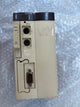 A vintage industrial electronic module, specifically a Mitsubishi TSX PF28S unit, shown from the rear. The beige plastic housing shows signs of wear, scuffs, and a sticker residue on the front panel, with dark gray/black connectors and a VGA port visible.