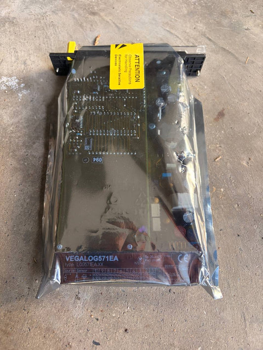 Vegalog Electronic component in clear packaging with a yellow label on a concrete surface