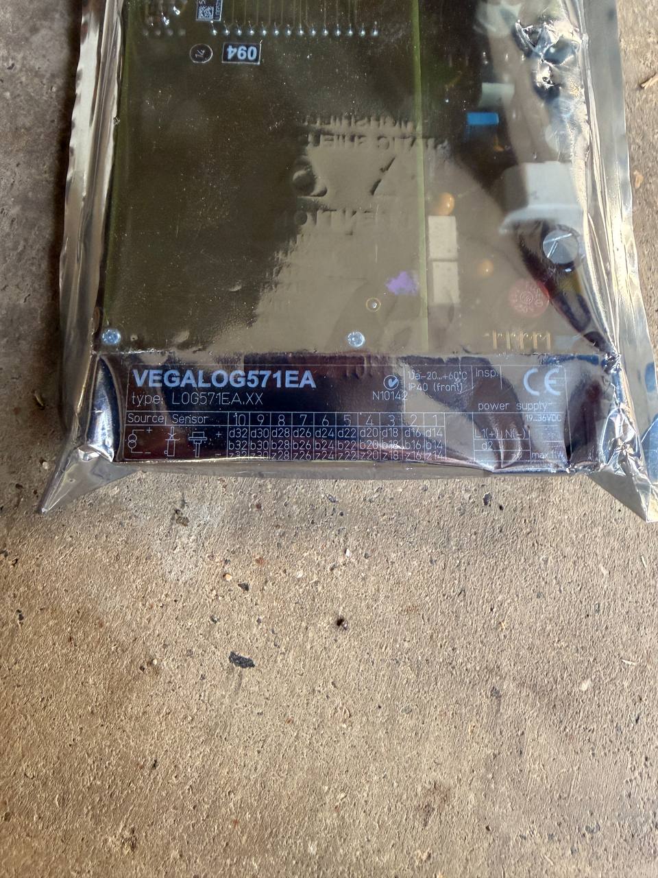 Electronic component with 'VEGALOG571EA' label on a concrete surface