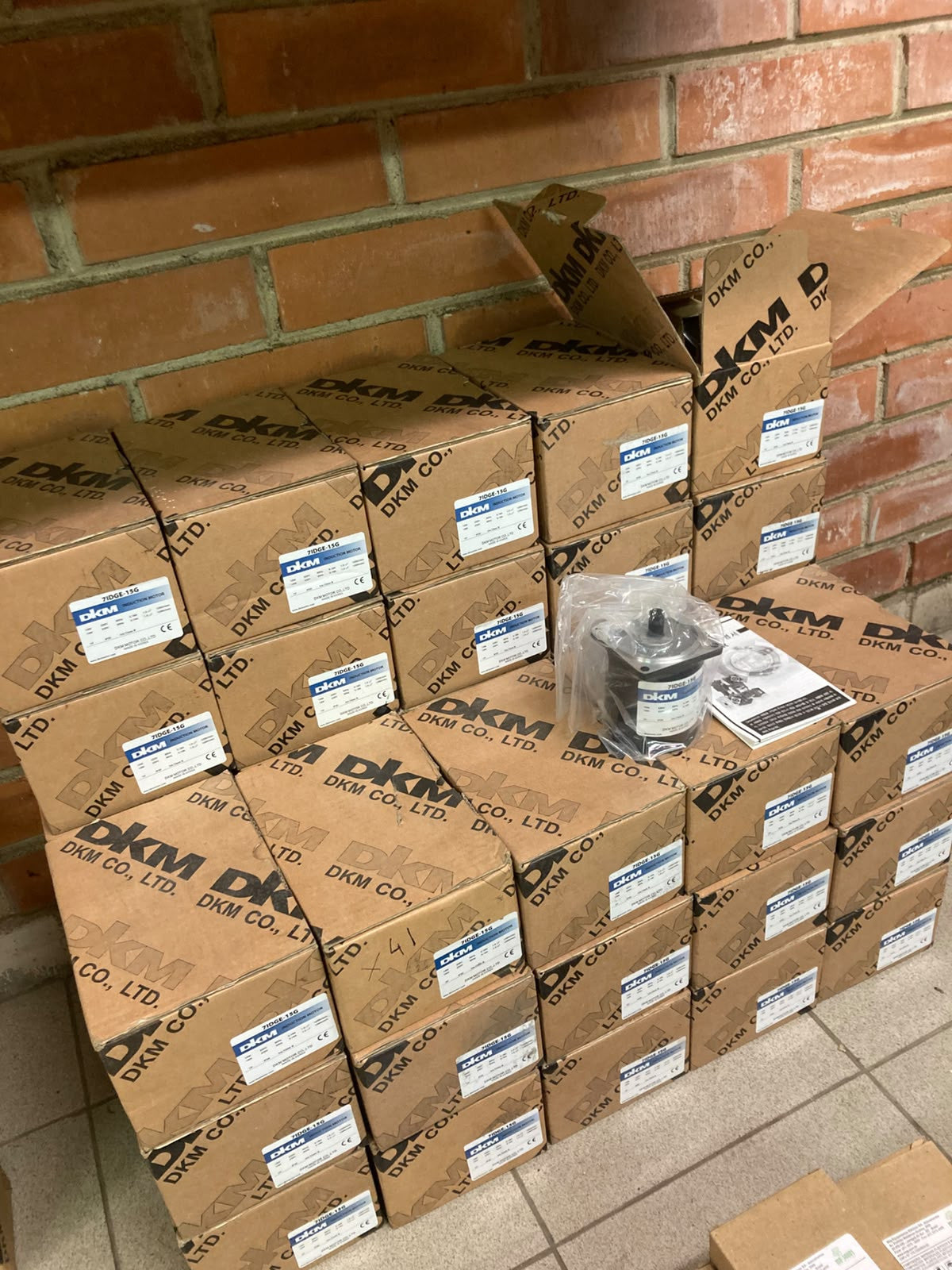 Stock of boxed DKM 7IDGE-15G induction motors, one unboxed on top
