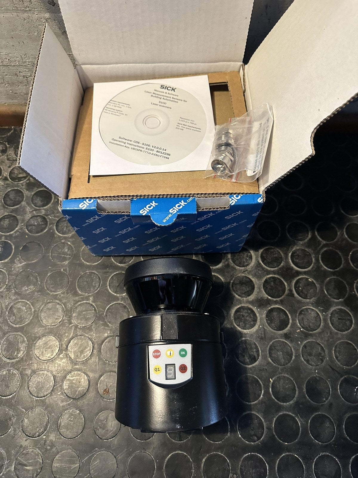 SICK S100 S10B-9011DA laser scanner with its open box, CD and mounting hardware